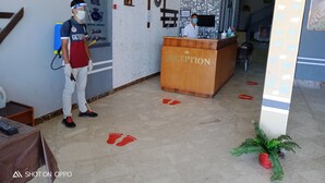 A hotel reception area with a reception desk labeled "RECEPTION," a sign for "ROYAL CROWN HOTEL," and a person standing near the reception.