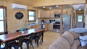 A wooden cabin interior with a dining area, kitchen, and a cozy living space.