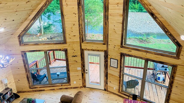 A cozy cabin interior with a wooden interior, large windows, a sofa, and a small table.