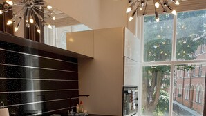 A modern kitchen with a black countertop, white cabinets, and a large window with a view of a building. - St Martins View - Two Bedroom Apartment, Sleeps 4 (York)