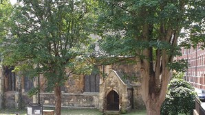 A stone building with a pointed arch entrance, surrounded by trees and a brick wall. - St Martins View - Two Bedroom Apartment, Sleeps 4 (York)