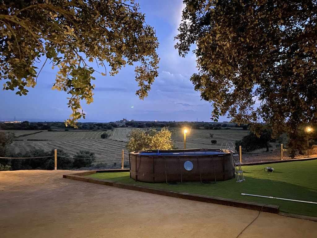 Une grande piscine rectangulaire avec un escalier, entourée d’une pelouse et d’arbres.