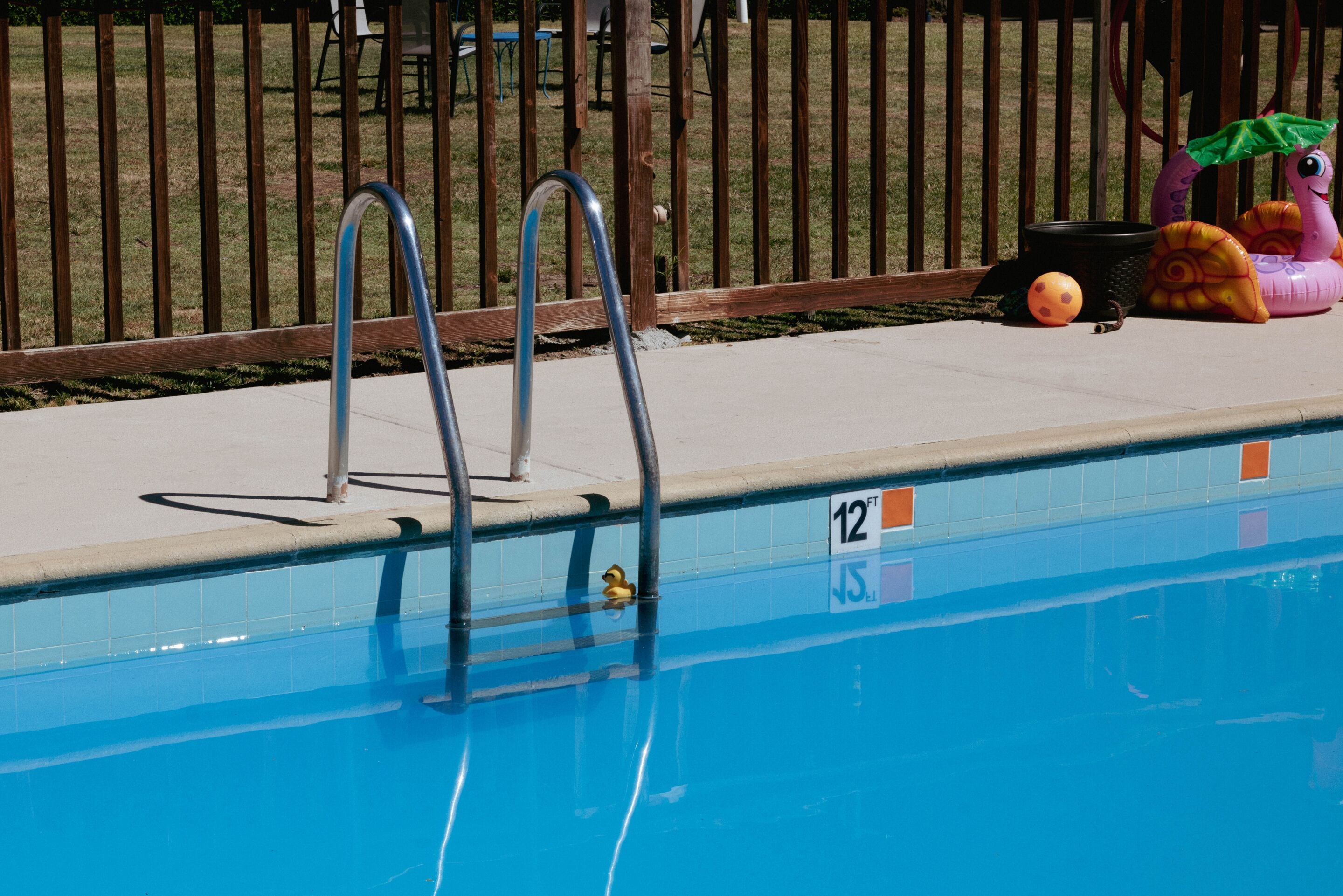 Piscina com escadas de metal, um pato de borracha e um brinquedo flutuante de caracol.