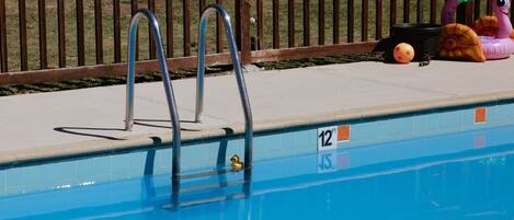 Piscina com escadas de metal, um pato de borracha e um brinquedo flutuante de caracol.
