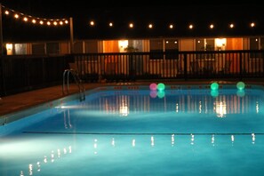 A swimming pool at night with string lights above.
