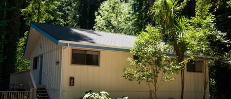 A small, single-story building with a sloped roof, a front door, and a small porch with steps.