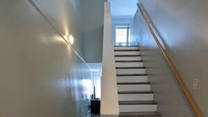 Eine Treppe mit Holzdielen und weißen Geländern, die zu einer oberen Etage führt.