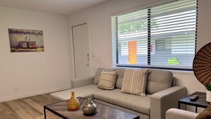 A modern living room with a sofa, a coffee table, and a painting on the wall. - Fort Lauderdale Beach Flats #6 - Centrally Located! (Fort Lauderdale)