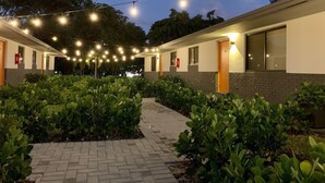A hotel corridor with a brick pathway, string lights, and greenery. - Fort Lauderdale Beach Flats #6 - Centrally Located! (Fort Lauderdale)