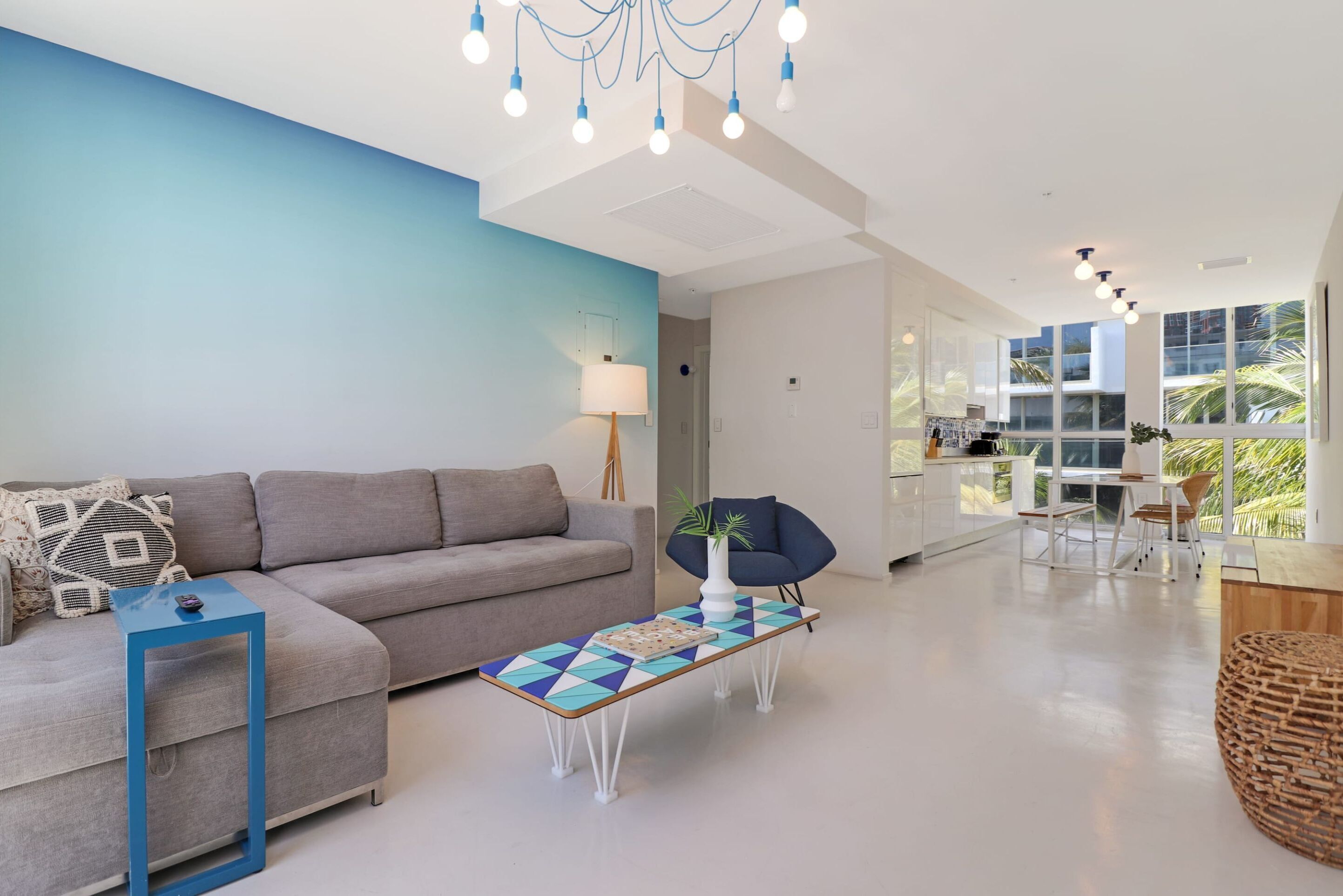 A modern living room with a grey sofa, a blue coffee table, and a blue chair.