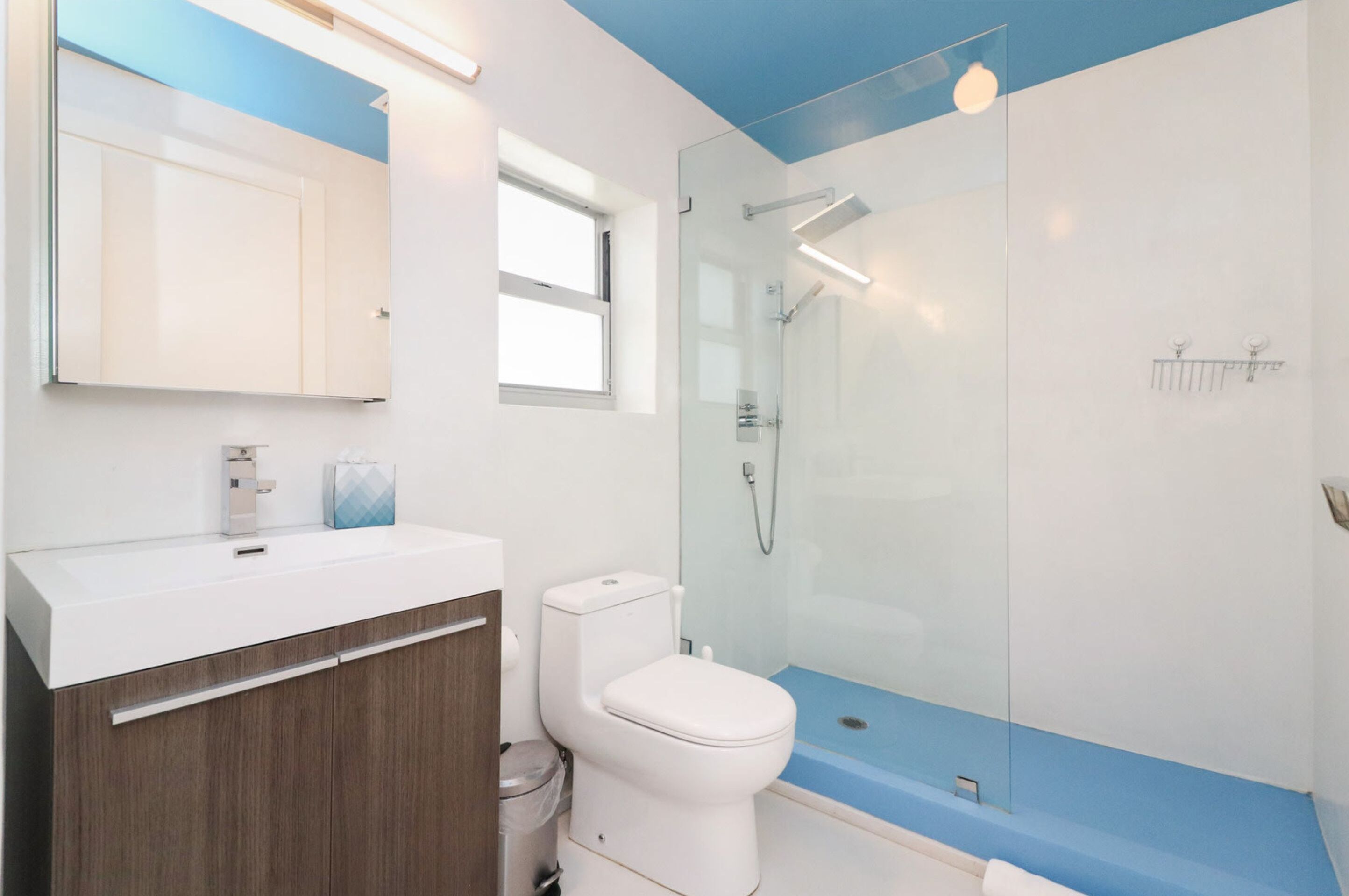 A modern bathroom with a glass-enclosed shower, a white toilet, and a vanity with a mirror and sink.