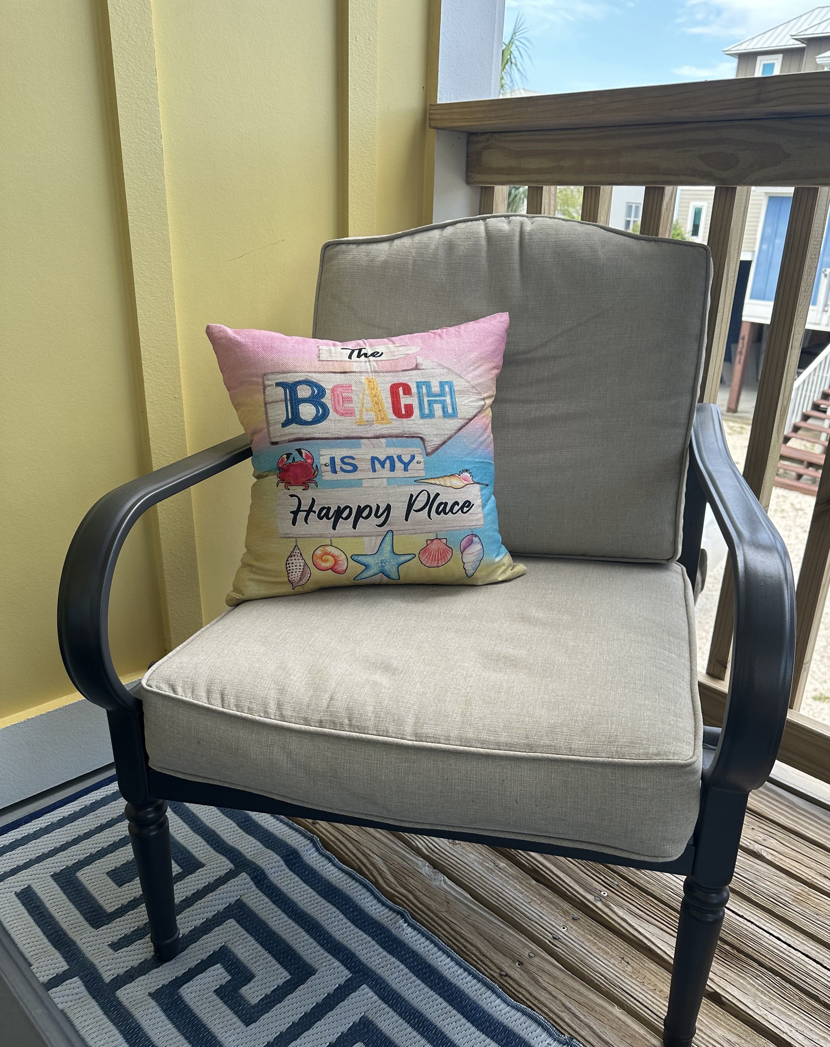 A chair with a cushion and a decorative pillow with text.