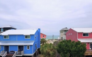 A coastal residential area with multi-story houses, including a blue house with a porch and a red barn-like structure. - 2 night minimum! Flexible Booking Dates! (Cape San Blas)
