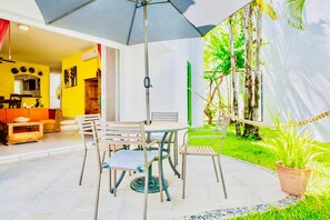 An outdoor patio with a table and chairs, a hanging umbrella, and a potted plant. - Dolce Vita Caribe Balcony Quadruple Room with Pool – Self Check-in - Playacar (Playa del Carmen)