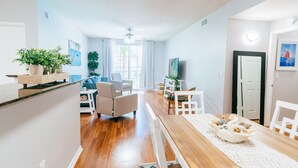 Uma sala de estar moderna com uma mesa de jantar de madeira, um sofá e uma televisão.