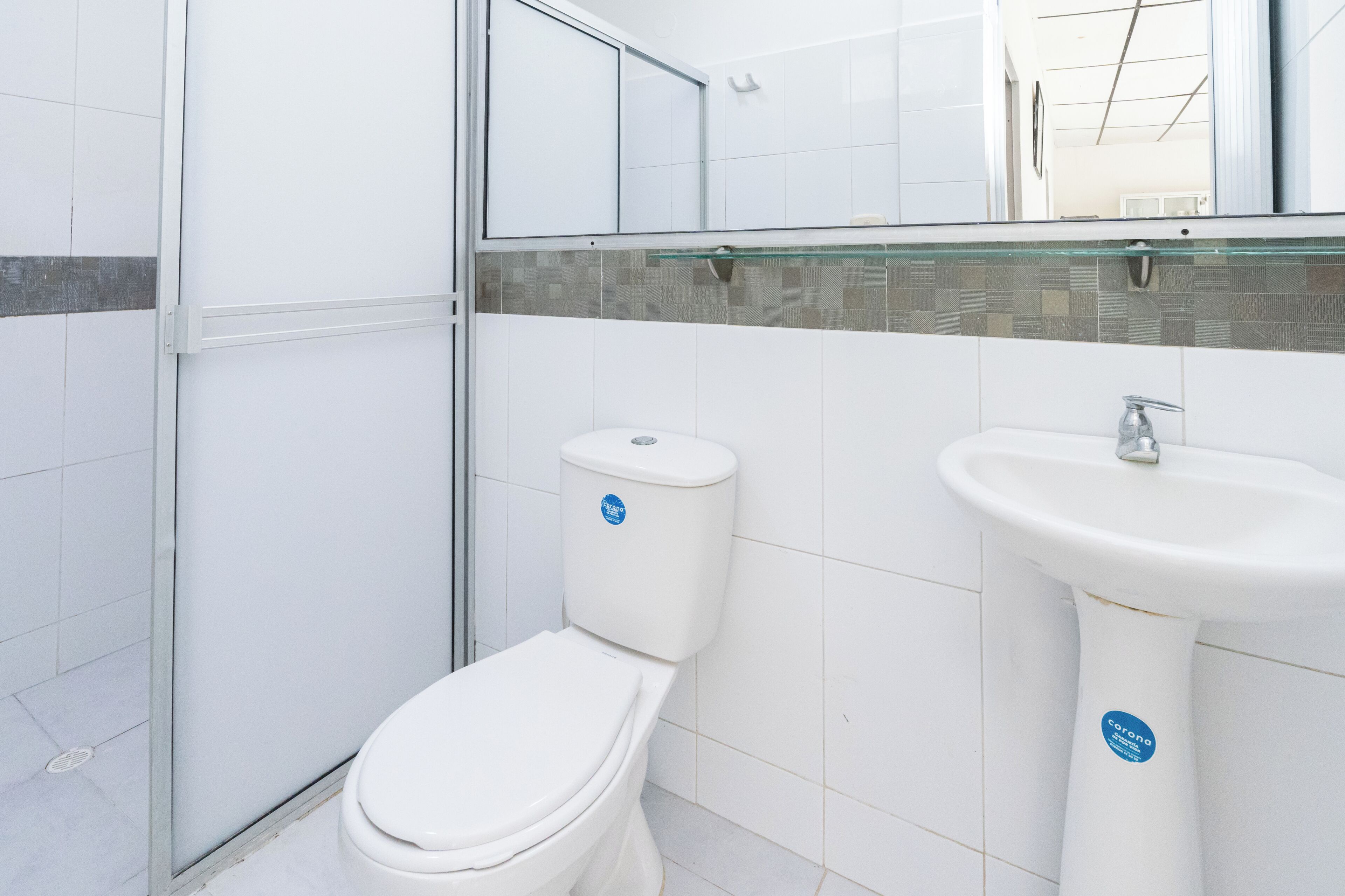 Un baño con inodoro, lavamanos y cabina de ducha de vidrio.
