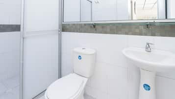 Un baño con inodoro, lavamanos y cabina de ducha de vidrio.
