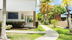 A modern building with a covered outdoor area, palm trees, and a pathway leading to a staircase. - Cabañas La Fragata Coveñas (Coveñas)