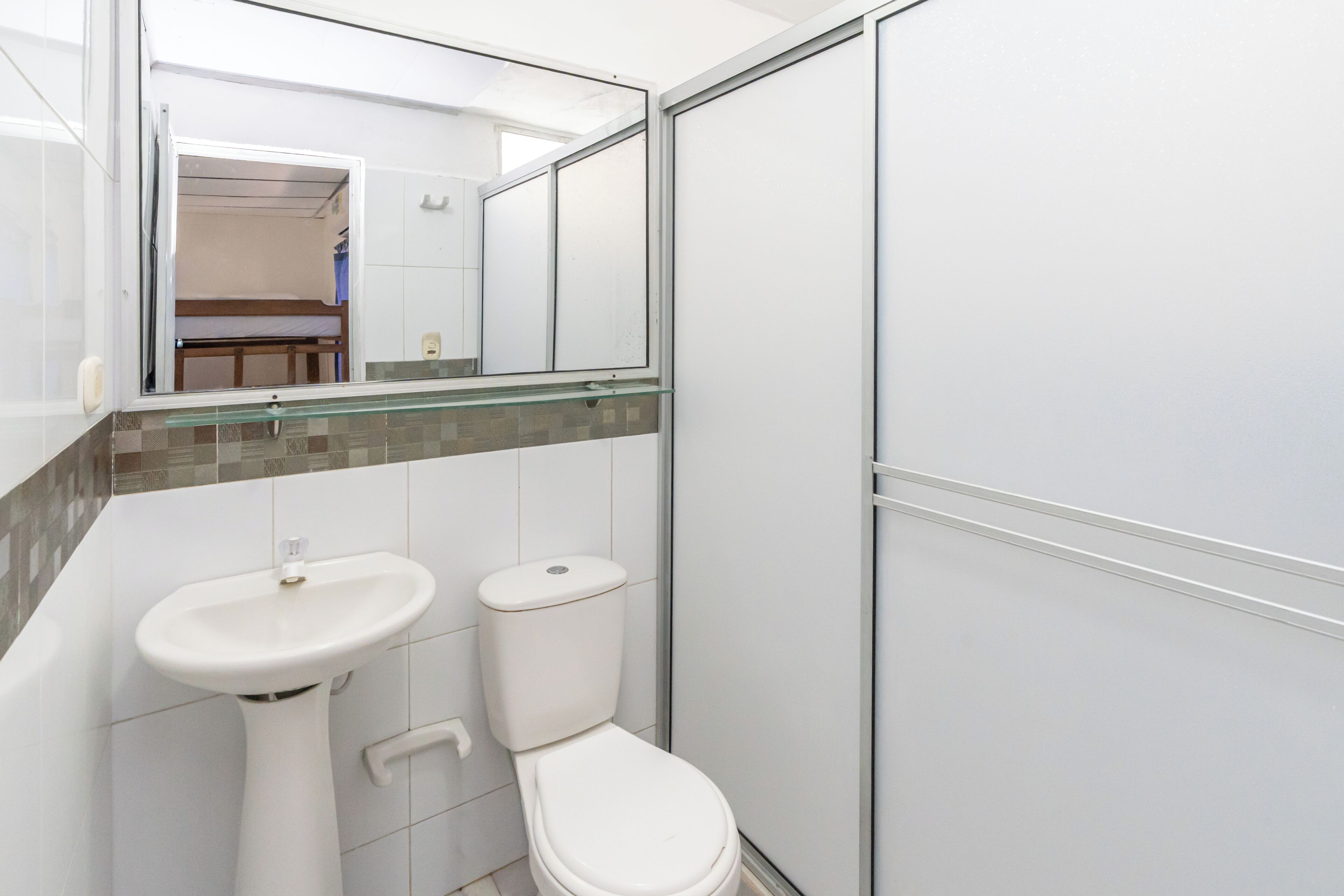 A bathroom with a white sink, toilet, and a glass shower enclosure.
