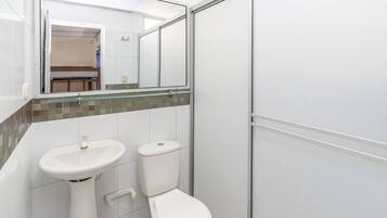A bathroom with a white sink, toilet, and a glass shower enclosure.