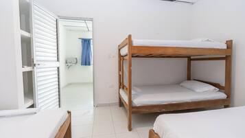Quarto com duas beliches, um guarda-roupa branco e uma porta para um banheiro.