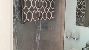 Un baño con una toalla estampada colgada en un perchero, un lavabo con espejo y una lámpara fijada a la pared.