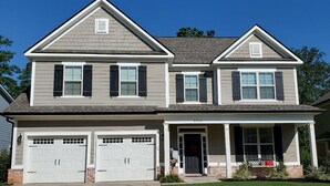 A two-story house with a front porch, two garages, and a small front yard. - Augusta Golf Course Rental Home MASTERS (Evans)