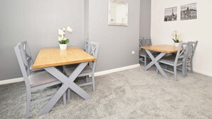 A room with two wooden tables and four grey chairs, each with a potted orchid. - Townhouse @ 86 Brooklyn Street Crewe (Crewe)