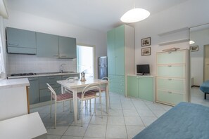 A compact kitchen with a dining table, chairs, and a TV.