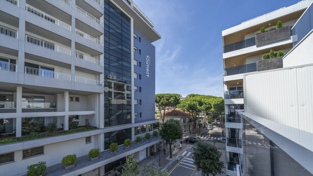 A multi-story building with balconies, a courtyard, and a street view.