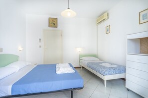 A room with two beds, a white dresser, and a door.