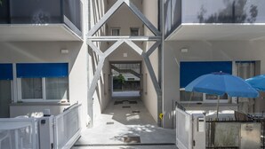 A building with a central corridor, metal railings, and a blue umbrella.