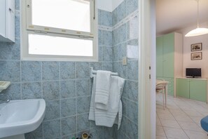 Une salle de bain avec un lavabo, une fenêtre et un porte-serviettes.