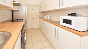 A modern kitchen with white cabinets, a wooden countertop, a built-in microwave, and a stainless steel refrigerator. - Townhouse @ 178 Ruskin Road Crewe (Crewe)