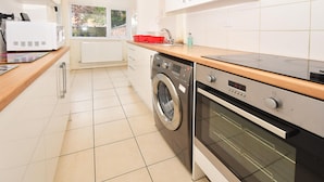 A modern kitchen with a washing machine, oven, and a red dish rack. - Townhouse @ 178 Ruskin Road Crewe (Crewe)