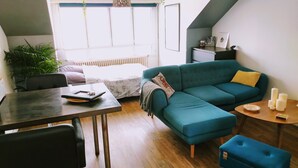 A modern living room with a teal sofa, a dining table, and a coffee table. - Connected studio with open view - CENTRE-VILLE (Nantes)