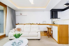 Una sala de estar moderna con un sofá blanco, una mesa de centro redonda y un aparador de madera.