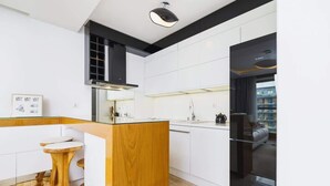 A modern kitchen with white cabinetry, a wooden island, and a black range hood. - Stylish Apartment with a Balcony | Parking | Close to Kazimierz (Kraków)