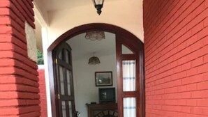 Un pasillo con paredes de ladrillo rojo, suelo de baldosas y un banco de madera.