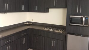 A modern kitchen with dark cabinetry, a gas stove, a microwave, and a stainless steel refrigerator. - Beautiful House on 2nd Floor (Close to the airport!)  (Tijuana)