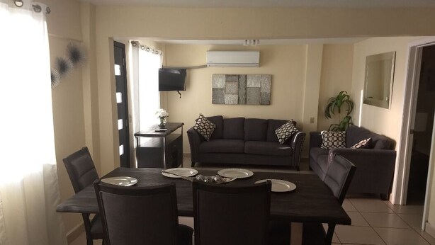 A dining area with a table set for four, a sofa, and a television in the background. - Beautiful House on 2nd Floor (Close to the airport!)  (Tijuana)