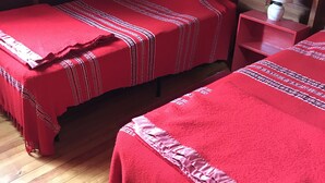 A room with two beds covered in red blankets, wooden walls, a small table with a lamp, and a framed picture on the wall. - Airy Wooden Beach House with Big Private Deck, close to Atlantic Ocean Beach or gentler bay swimming.  (Fire Island)