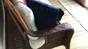 A cozy corner with a wicker sofa, a small table, and a bench with plaid cushions. - Airy Wooden Beach House with Big Private Deck, close to Atlantic Ocean Beach or gentler bay swimming.  (Fire Island)