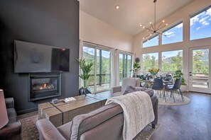 Una sala de estar moderna con chimenea, ventanas amplias y un comedor con vistas al exterior.