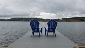 Two blue Adirondack chairs on a wooden dock extending into a lake, with a cloudy sky above. - Lovely Mount Storm Waterfront Lake House - pet friendly, child friendly retreat (Mt Storm)