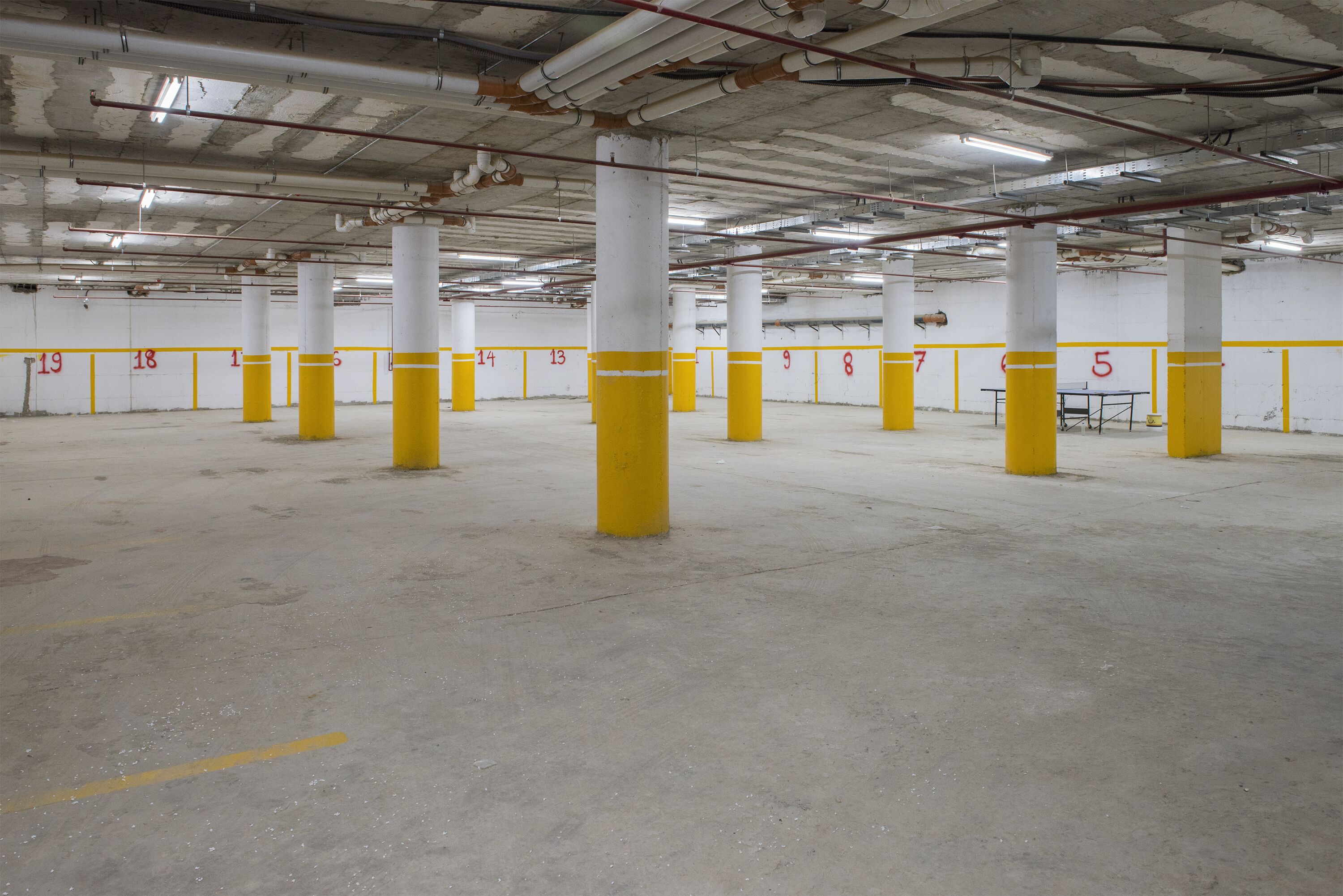 En parkeringskælder med nummererede parkeringspladser og gule søjler.