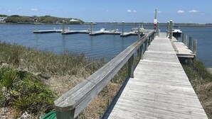 Un muelle de madera que se adentra en aguas tranquilas, con muelles y barcos.