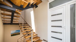 A modern staircase with wooden steps and metal railings, leading to a white door with multiple panels. - Apartments Ema-Comfort Two Bedroom Apartment with Sea View (Rogotin)