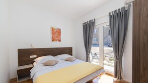 A bedroom with a bed, a bedside table, a window with curtains, and a view of the outside. - Apartments Ema-Comfort Two Bedroom Apartment with Sea View (Rogotin)