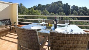 A terrace with wicker chairs and a table set for two, overlooking a forested area. - Bernia Golf by Interhome (Altea)